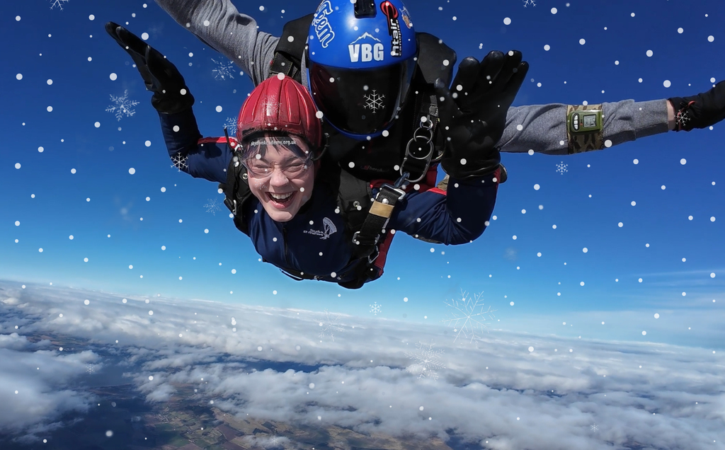 Tandem skydivers with arms out-stretched, with snow imagery overlayed