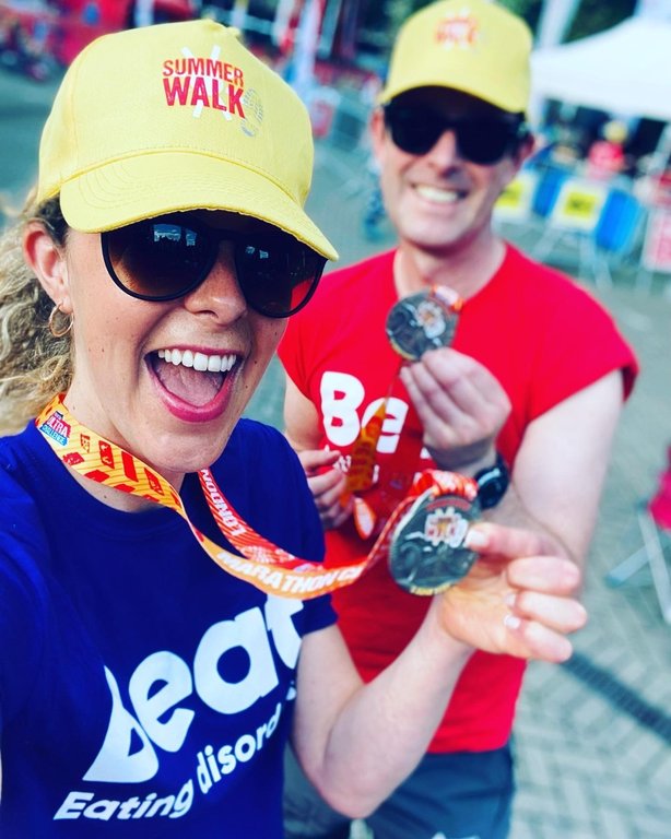 Woman and man holding medals wearing Beat t-shirts