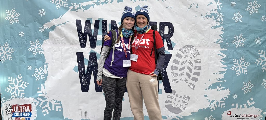 Two women standing next to each other in Beat t-shirts wearing winter walk bobble hats
