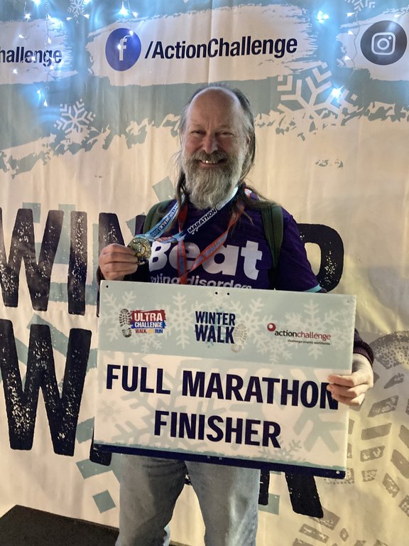 Man holding a medal and certificate wearing a purple Beat t-shirt